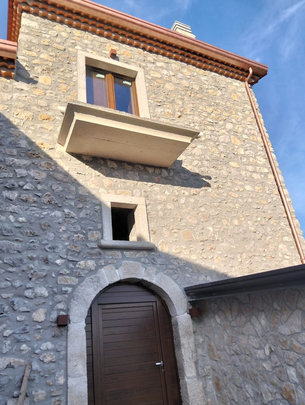 Facciata in pietra restaurata dell’Antico Frantoio Petrucci con ingresso ad arco