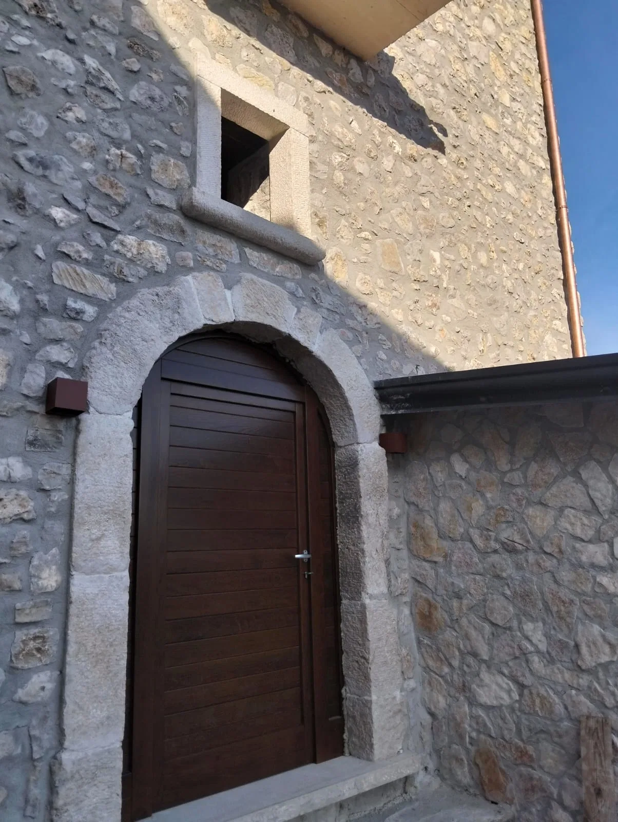 Dettaglio del portone in legno sotto un arco in pietra restaurata